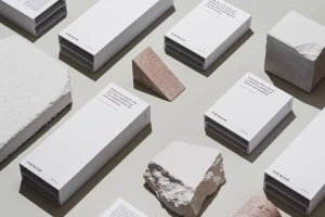 Overhead flat lay of white Henua Organics product boxes arranged with textured stone blocks on a neutral grey background