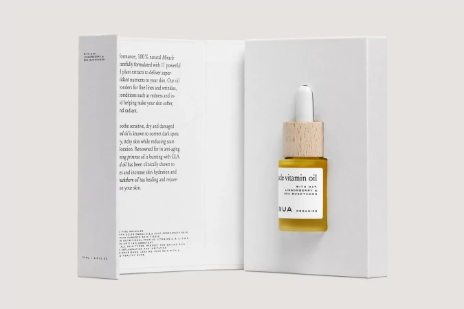 Skincare product packaging open to reveal a dropper bottle of facial oil inside a white cardboard presentation box.