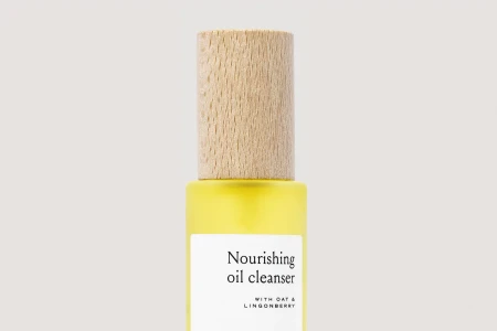 Close up product shot of a skincare bottle with a wooden cap against a neutral background for Henua Organics brand identity.