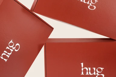 Three red boxes featuring white Hug branding arranged diagonally against an off-white background
