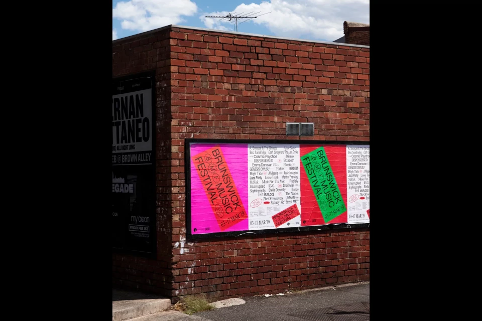 Brick wall with posters for the Brunswick Music Festival; street setting, daytime lighting.