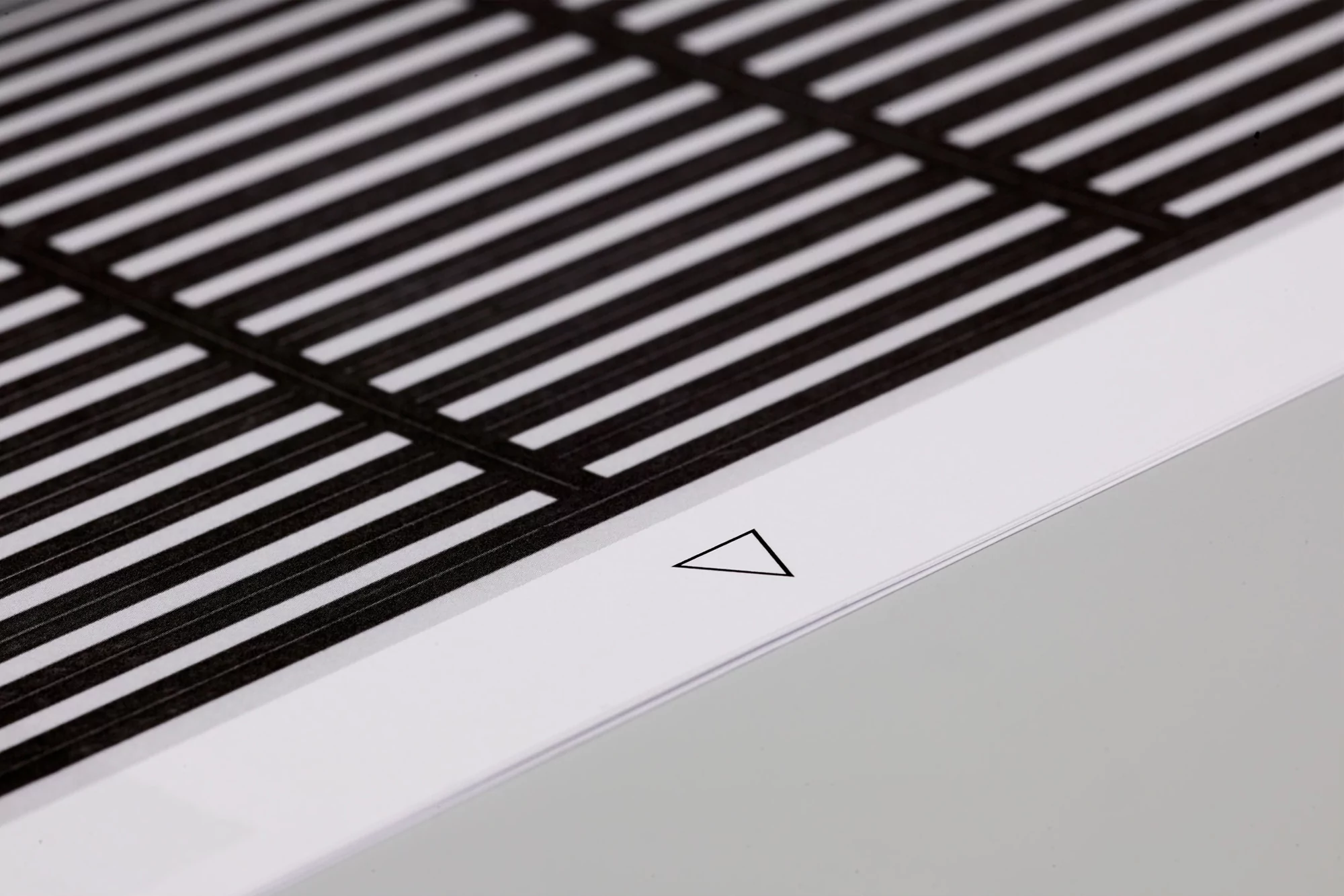 Black and white abstract image of parallel lines intersected by perpendicular lines, creating a grid-like pattern, with a white triangle.