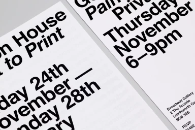 Close-up of printed graphic design typography on white paper sheets featuring bold black event details.