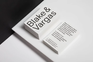 Stacks of white business cards with bold black typography on a contrasting surface for Blake & Vargas brand identity.