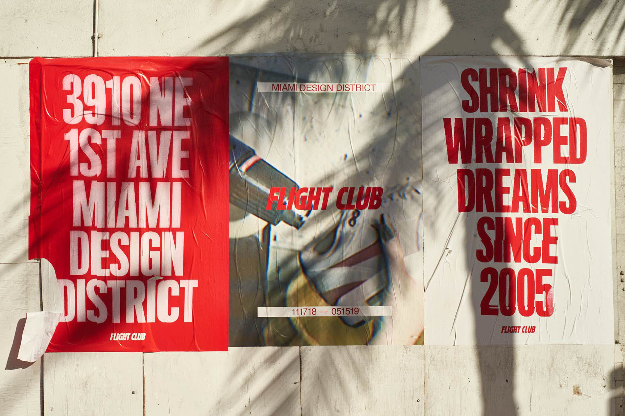 Posters on a wall advertising Flight Club, with a Miami Design District address and dates. Red and white color scheme.