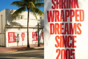 Diptyque poster campaign on white building exterior with palm tree and street lamp