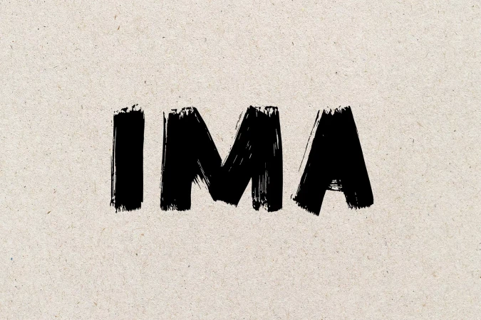 Brushstroke style black text 'IMA' on a textured beige background, creating a bold and artistic graphic element with a handmade feel.