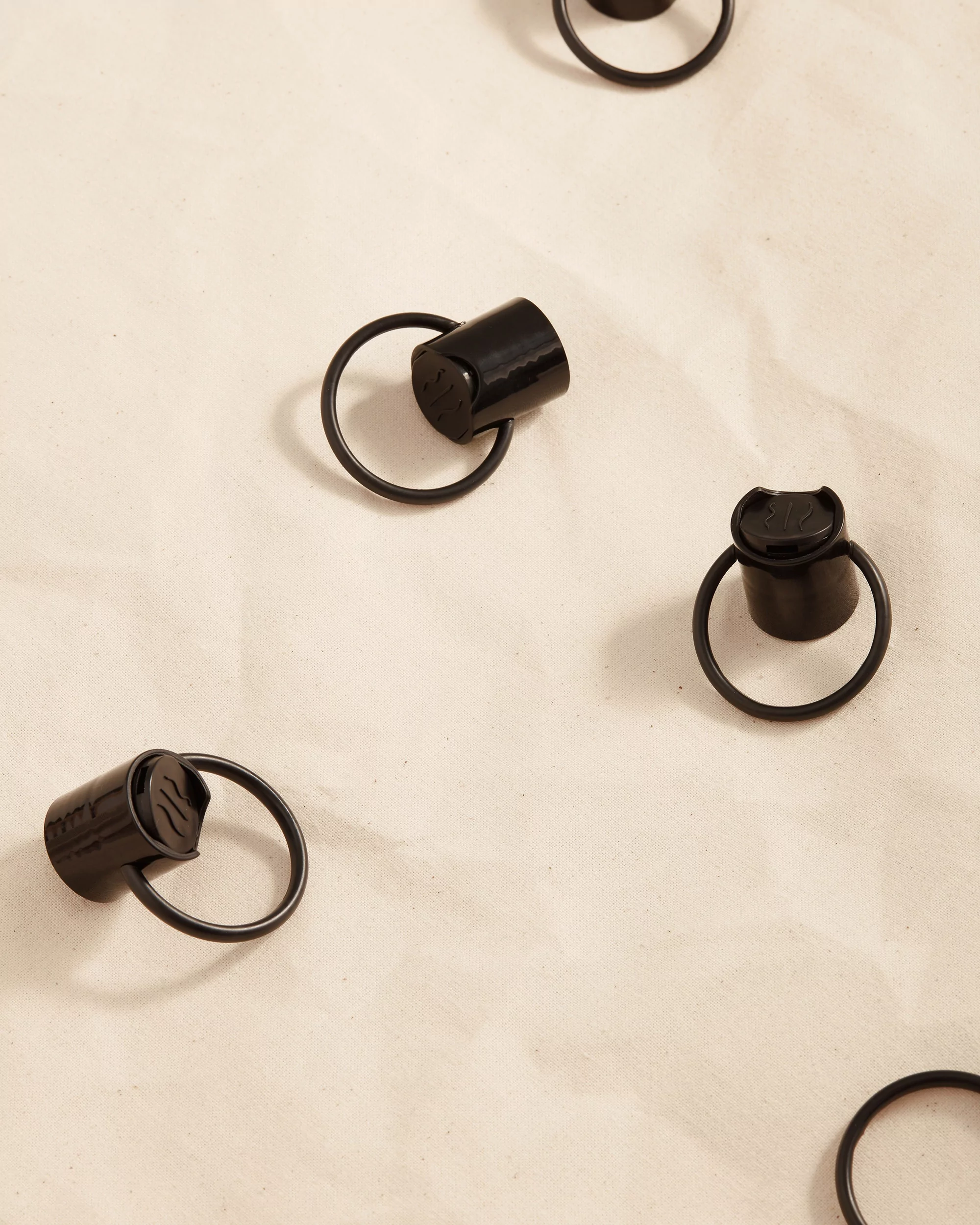 A seamless pattern of black metal rings with small caps, evenly spaced on a mottled off-white surface, suggesting a modern design.