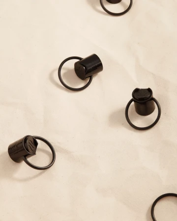 A seamless pattern of black metal rings with small caps, evenly spaced on a mottled off-white surface, suggesting a modern design.