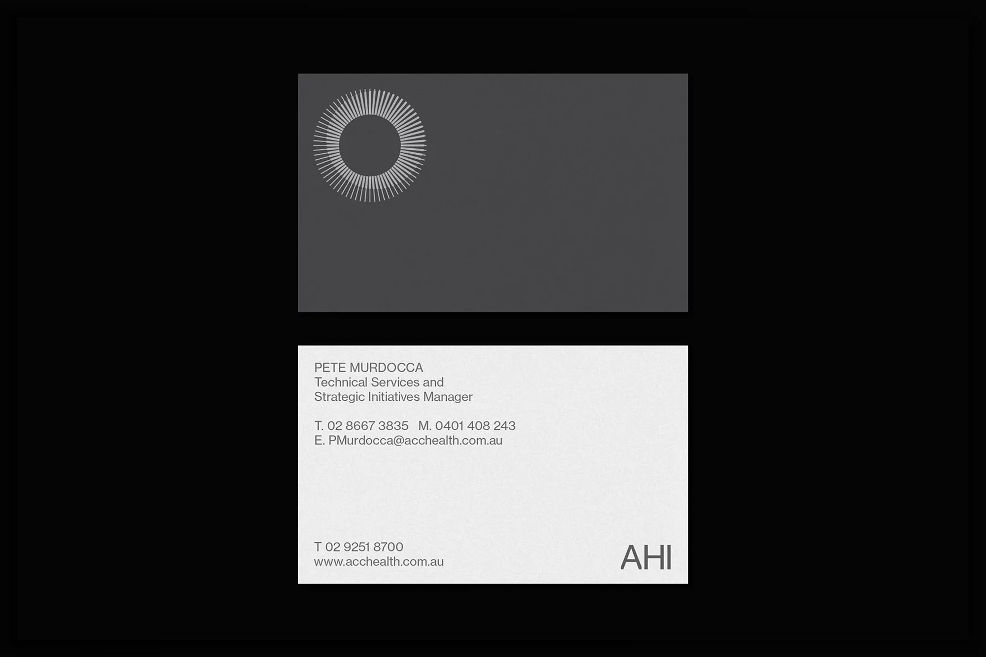 Two business cards, one gray with a white radial logo, the other white with contact information, on a black background.
