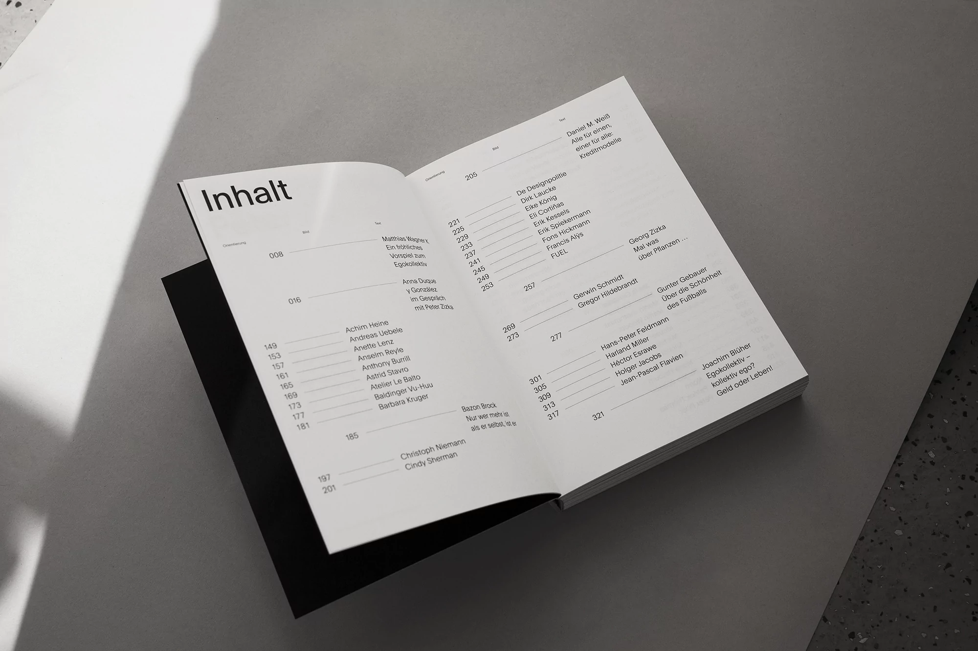 Open book with pages displaying text content, presented in a studio setting with neutral gray background.