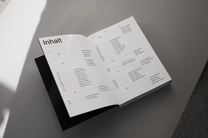 Open book with pages displaying text content, presented in a studio setting with neutral gray background.
