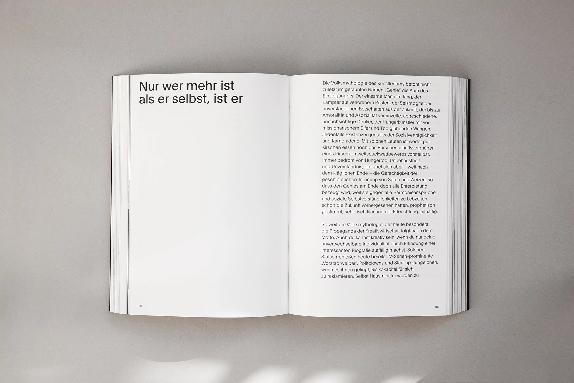 Opened book displays a page of dense German text on the right and partial text on the left, against a grey background.