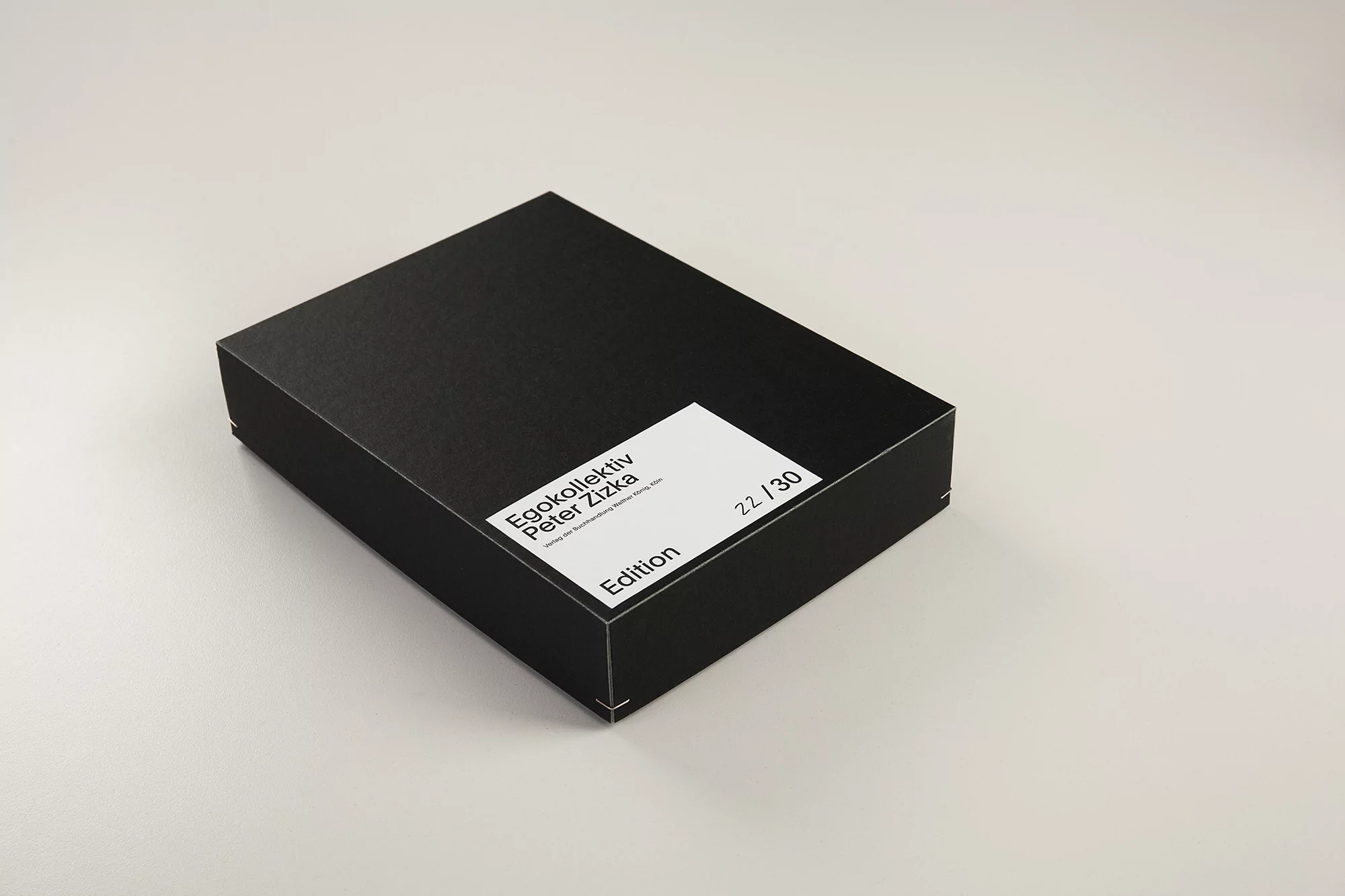Studio shot of a closed black box with a white label displaying text, set against a neutral background, creating a simple aesthetic.