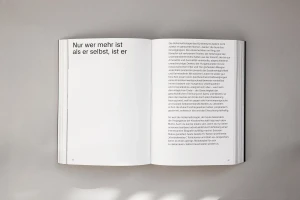 An open book with German typography displayed flat on a plain grey surface.