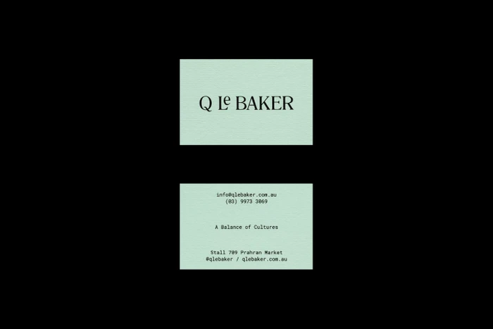 Two light green business cards for Q Le Baker displayed against a solid black background, featuring typography and contact details.