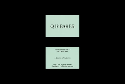 Two light green business cards for Q Le Baker displayed against a solid black background, featuring typography and contact details.