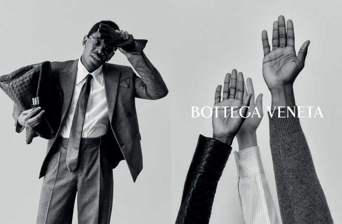 A man in a suit holding a woven leather bag is featured alongside a group of raised hands in a black and white fashion ad.