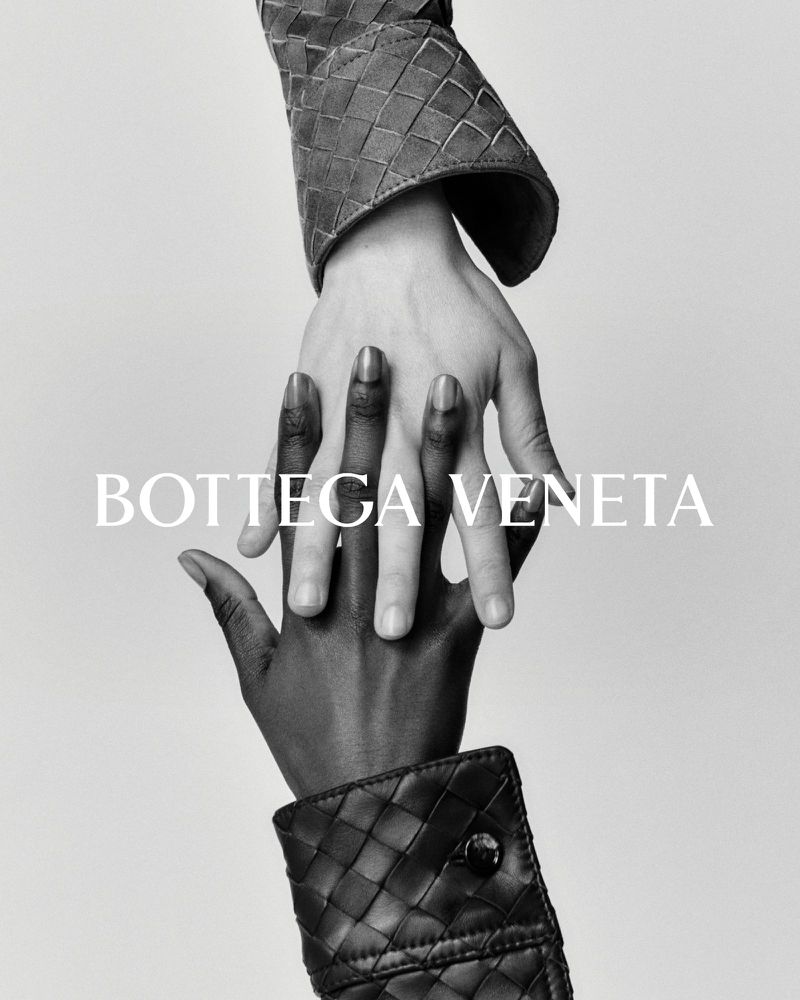 Interlocking hands in a black-and-white studio shot featuring Bottega Veneta woven leather cuffs, showcasing high-fashion textures.