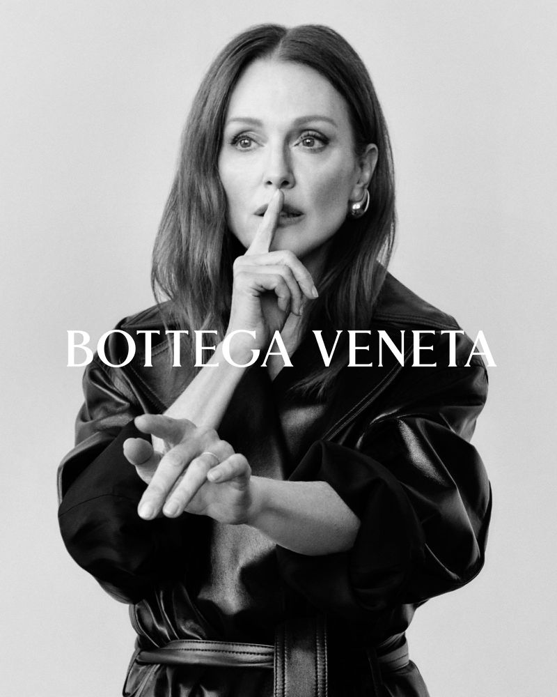 Black and white studio shot of a woman with long hair wearing a black leather coat, gesturing for silence, and featuring Bottega Veneta text overlay.