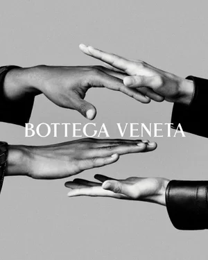 Close-up black and white image of hands gesturing against a solid background with Bottega Veneta text.