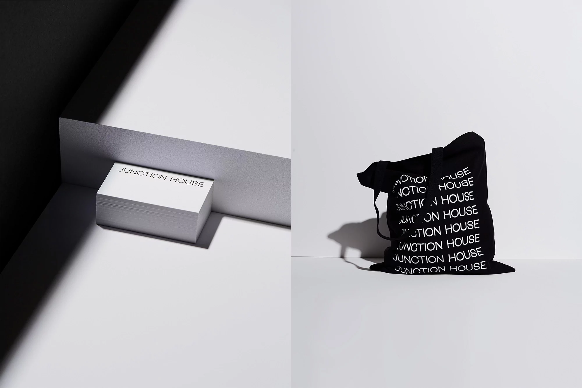 Elevated presentation of business cards and a tote bag with text in a minimalist studio setting with stark light and shadows.