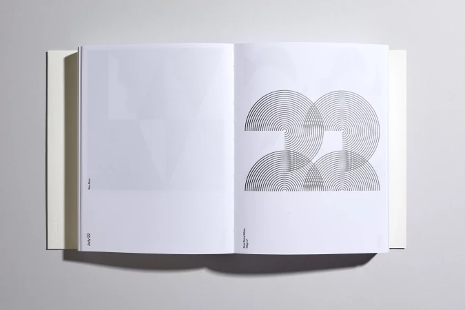 Open book displays graphic design with concentric circles creating an abstract image on a white page, presented in a minimalist style.