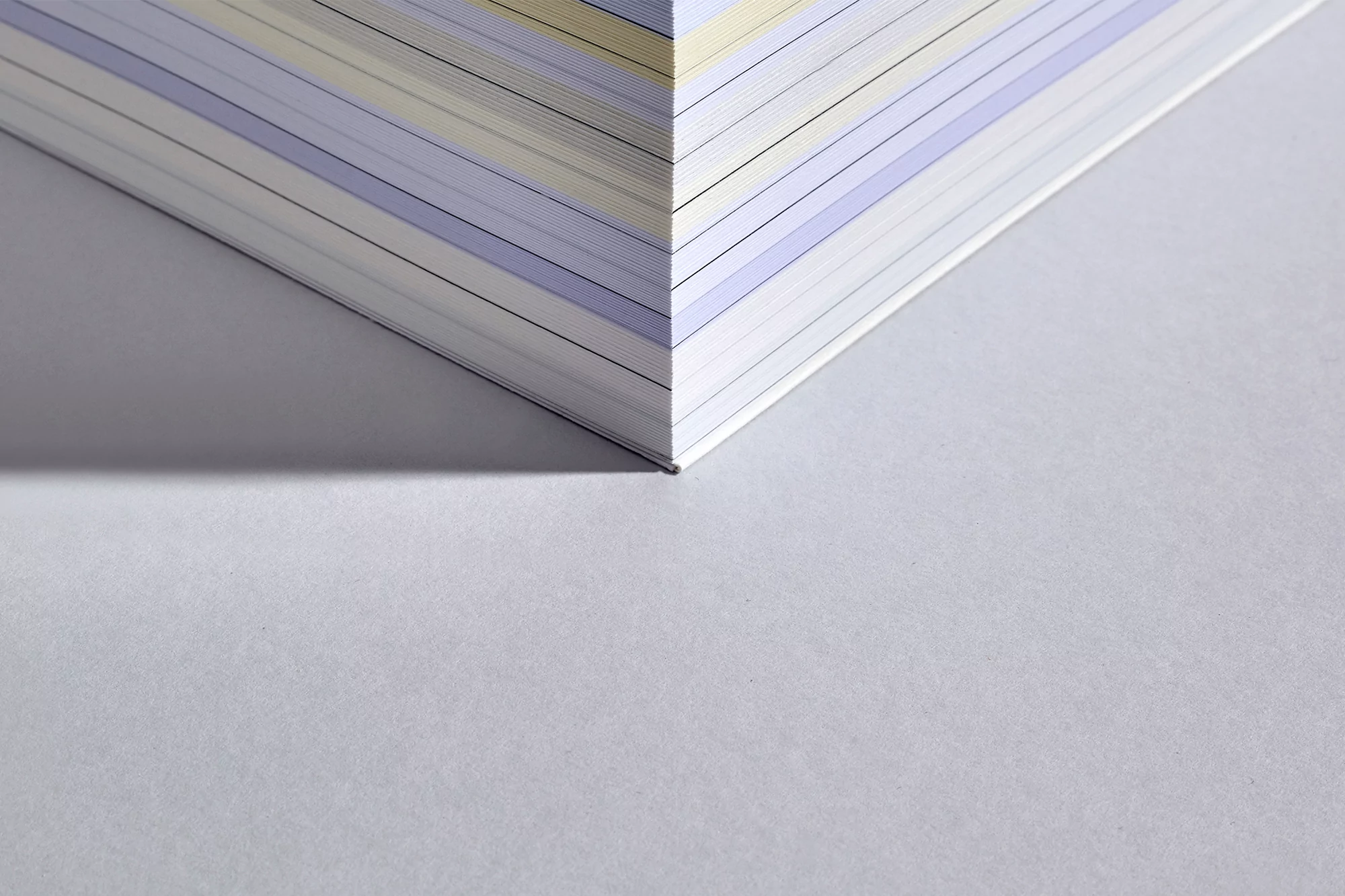 Close-up shot of a book's corner with paper edges visible, showcasing a blend of light and dark shadows on a textured surface.