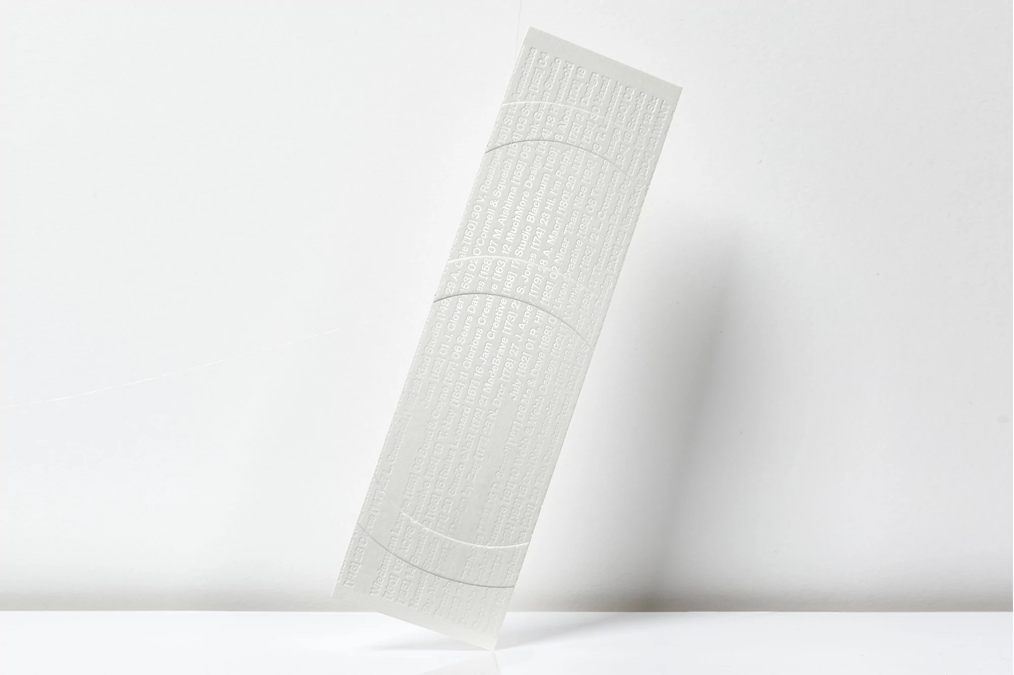 Minimalist shot of white embossed paper with circular details on a glossy surface against a white background, creating a clean and textured look.