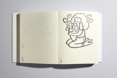 An open notebook on a grey surface showing printed outline illustrations of a person hugging a heart with the number 14.