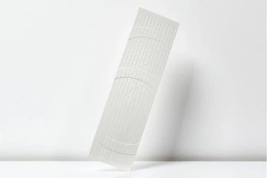 Vertical strip of white textured paper with embossed typography against a plain white studio background