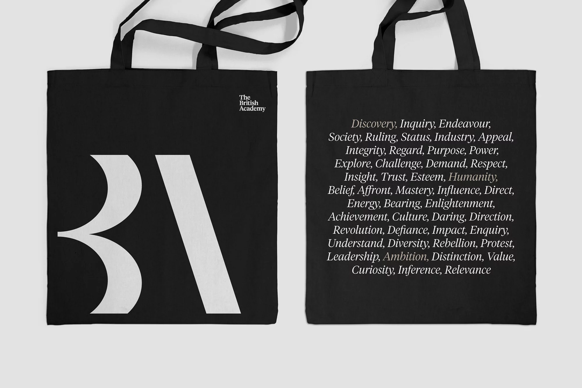 Two black tote bags featuring white text and logos are displayed on a white background. One bag has the letters BA in large font.