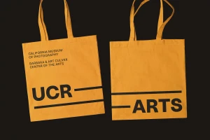 Two yellow tote bags with black typographic branding displayed against a dark background, designed by Forth + Back for UCR Arts.