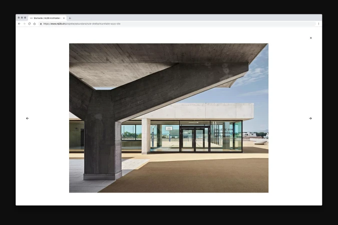 Architectural photograph showcases a modern building with concrete supports, glass windows, and a basketball court, set against a bright sky.