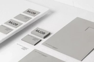 Minimalist stationery set featuring business cards and letterhead with MJ2B branding on a textured white surface