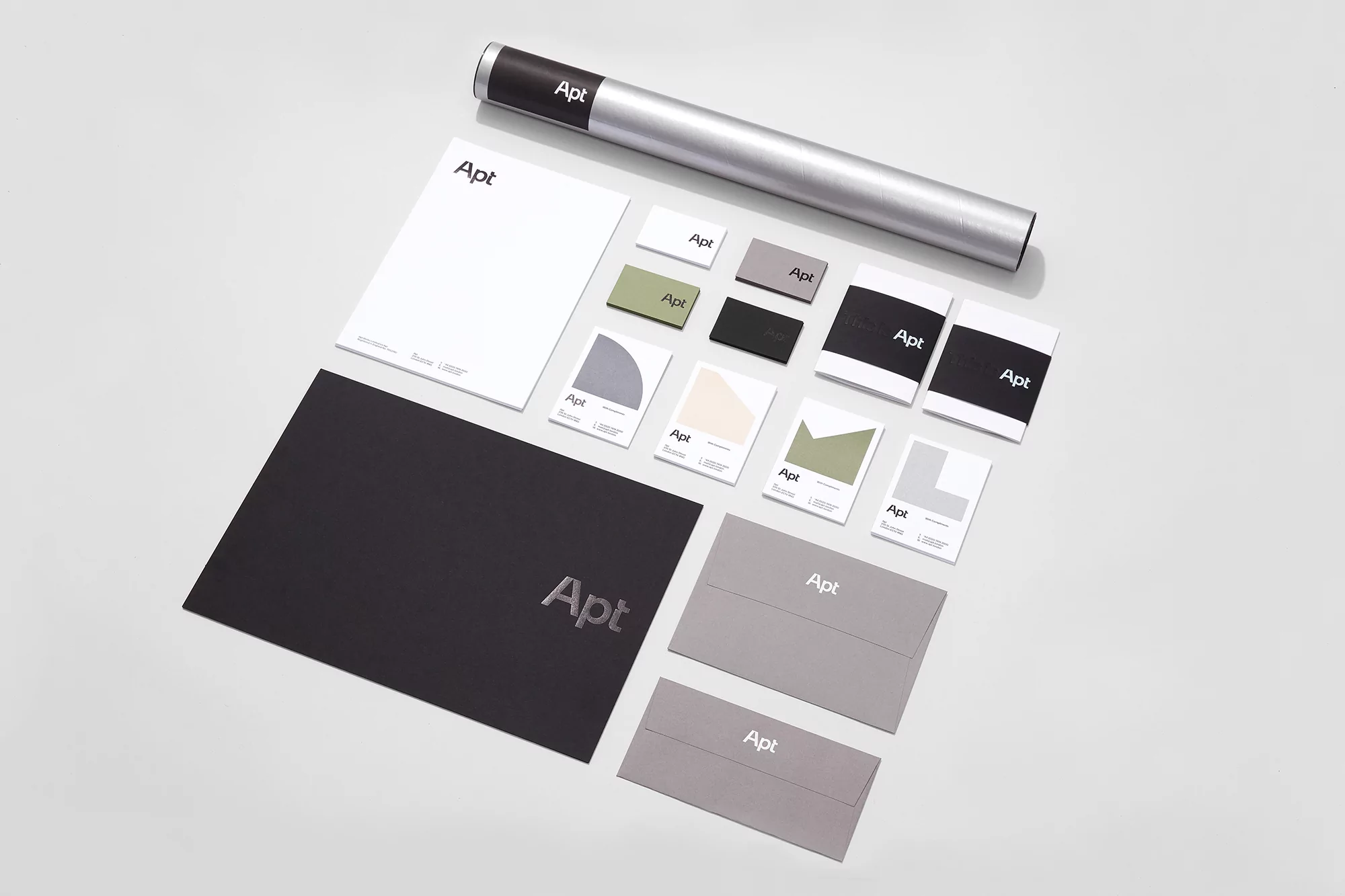 A flat lay of Apt-branded stationery, including a black folder, envelopes, cards, and color swatches, neatly arranged on a white background.