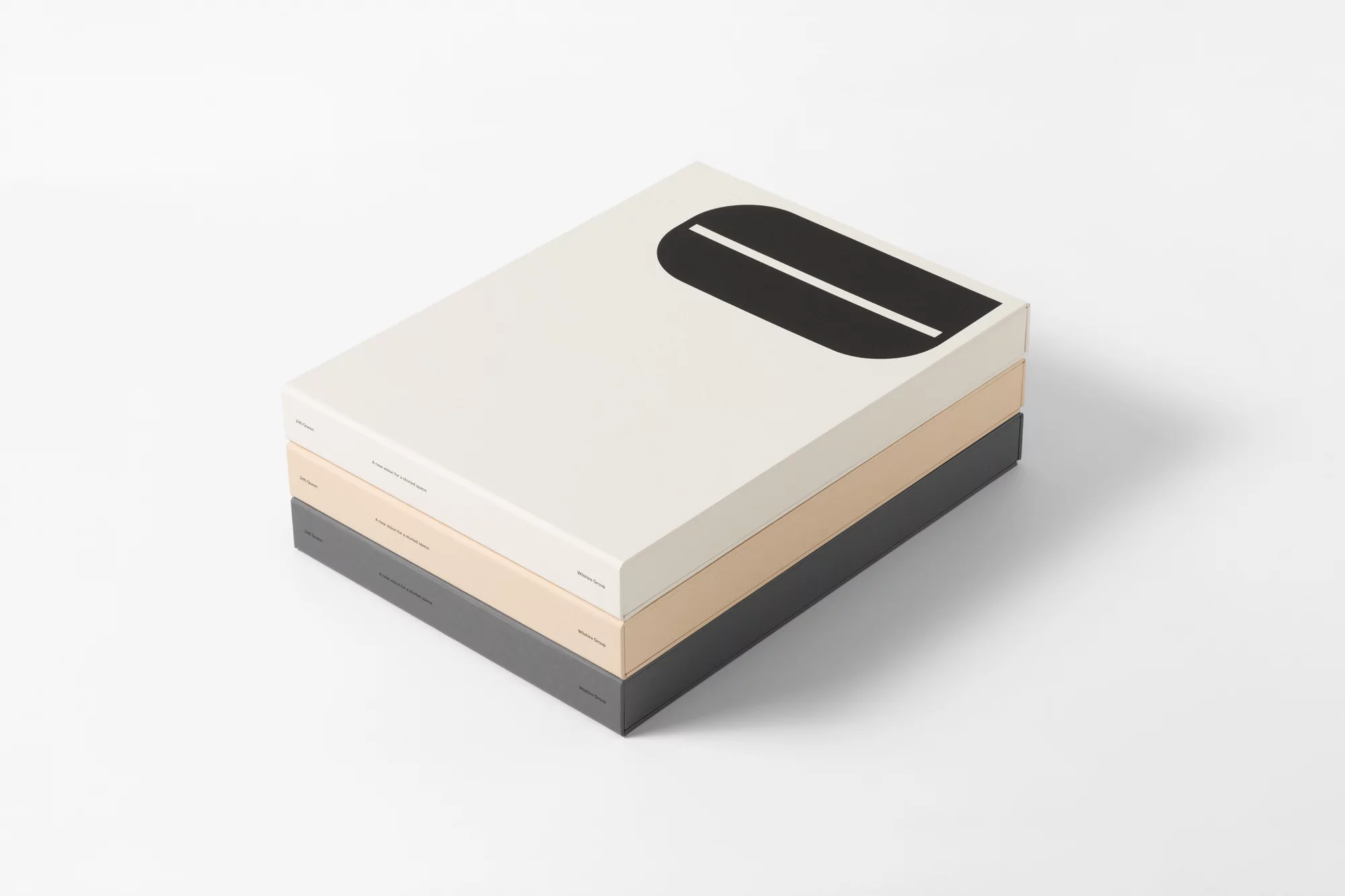 Stack of three boxes, the top one is white with a black design. The middle one is beige and the bottom one is gray.