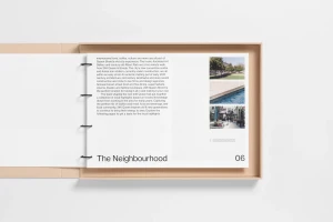 Open ring-bound brand identity booklet with editorial typography resting inside a beige box tray on a white surface.