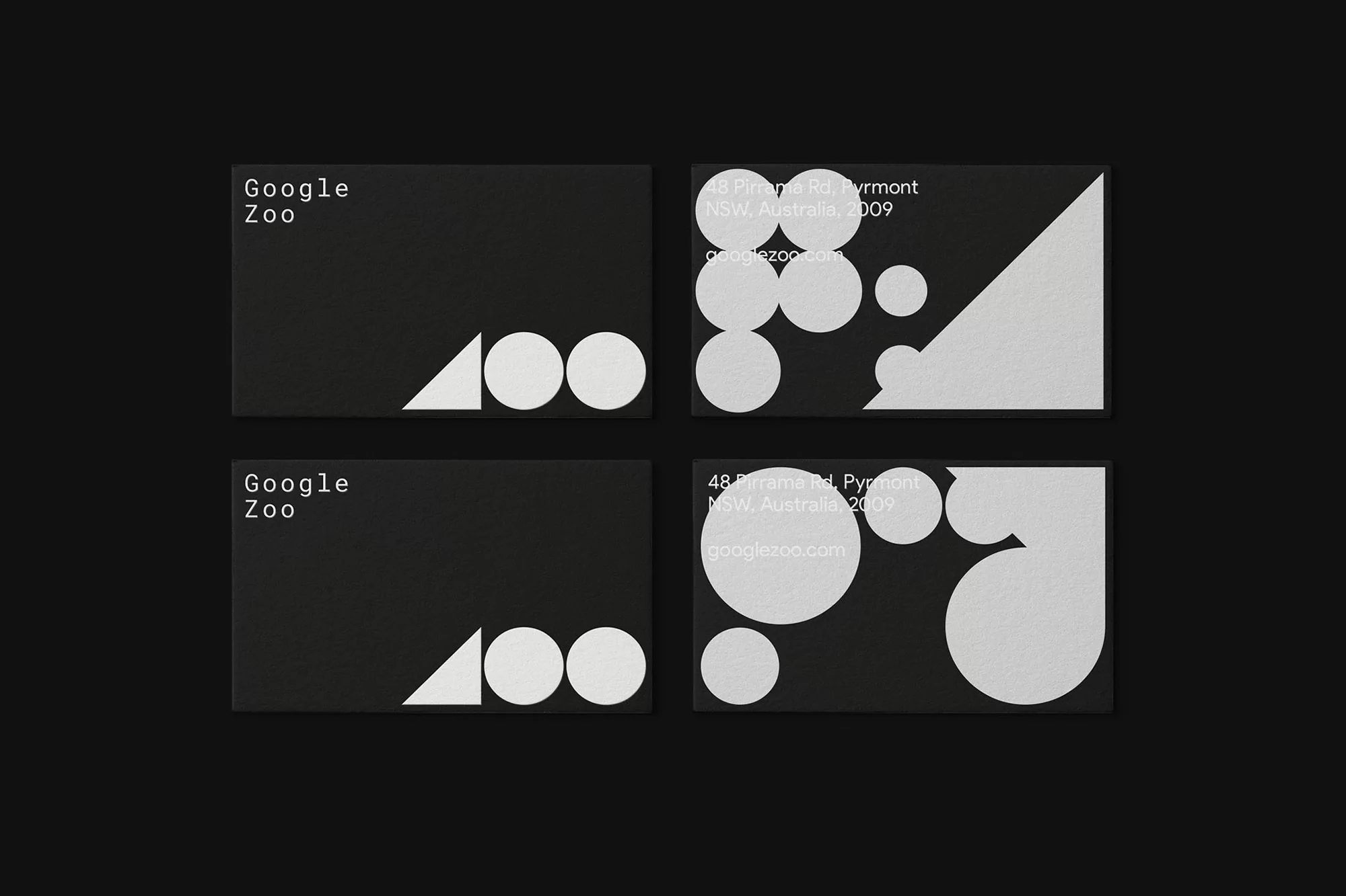 Four business cards featuring geometric designs and company branding on a dark background, showcasing minimalistic design.