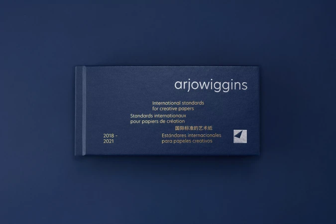 Arjowiggins paper sample book on a blue background, showcasing international standards for creative papers from 2018 to 2021.