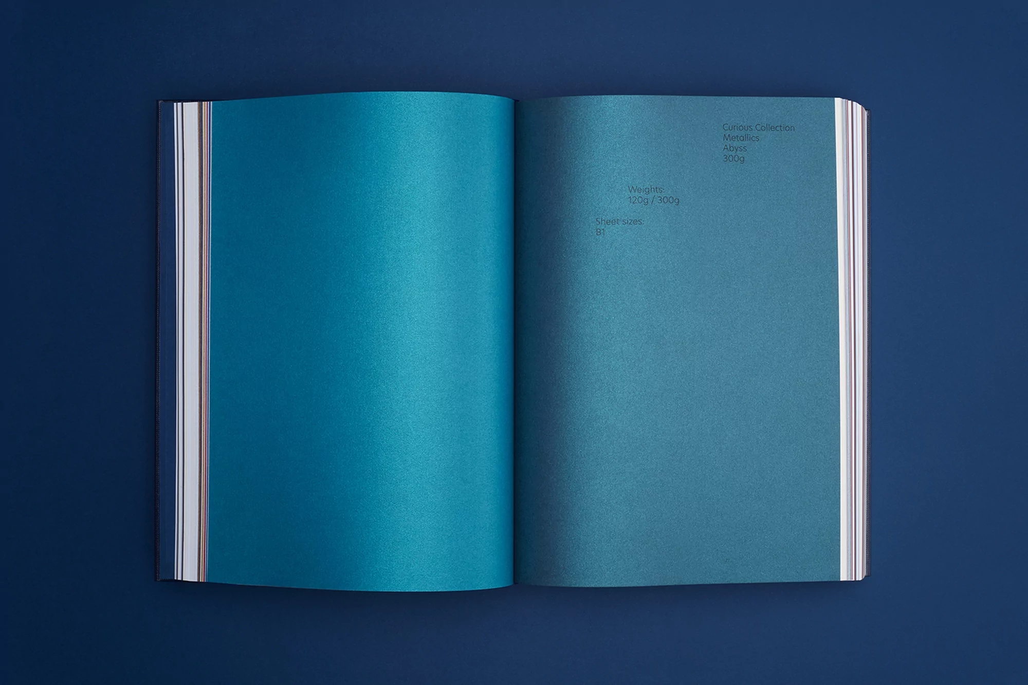 Open book displays two shades of blue paper against a dark blue background, emphasizing texture, color, and material.