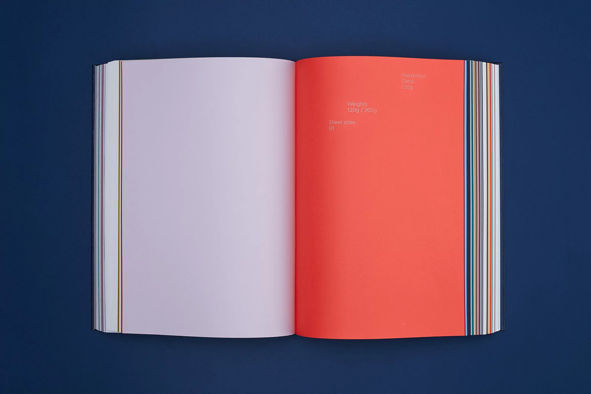 Open book on a dark blue surface, featuring an orange right-hand page with visible text and a violet-tinted left-hand page.