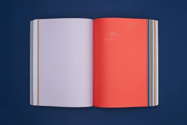 Open book showcasing colorful creative papers with a vibrant coral page and light purple page against a dark blue background
