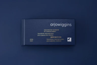 Dark blue textured paper book with white and silver typography on a solid blue surface.