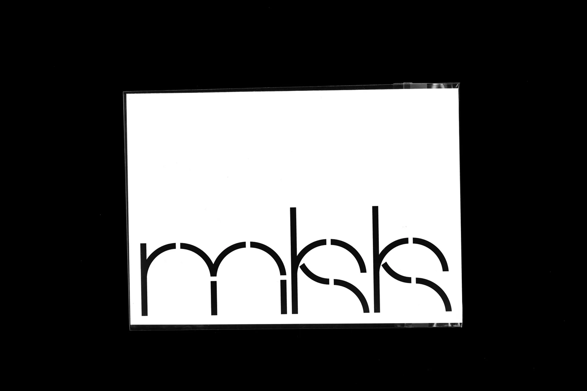 White card with black cutout text on a black background. Modern graphic design with text: mks.