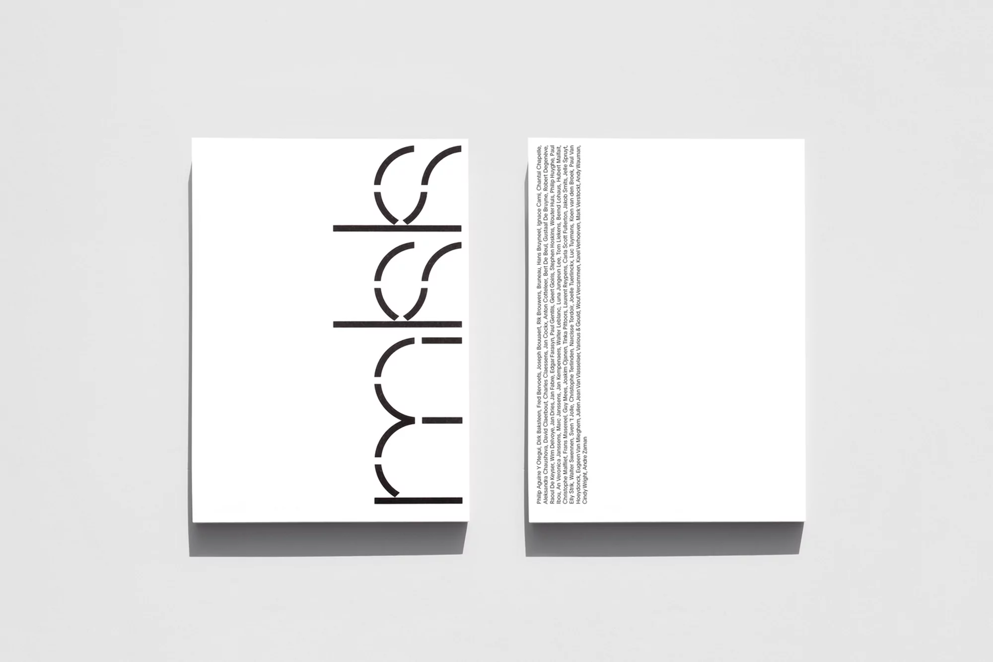 Two white paper sheets displaying modern minimalist typography, showcasing black font on white background in graphic design composition.