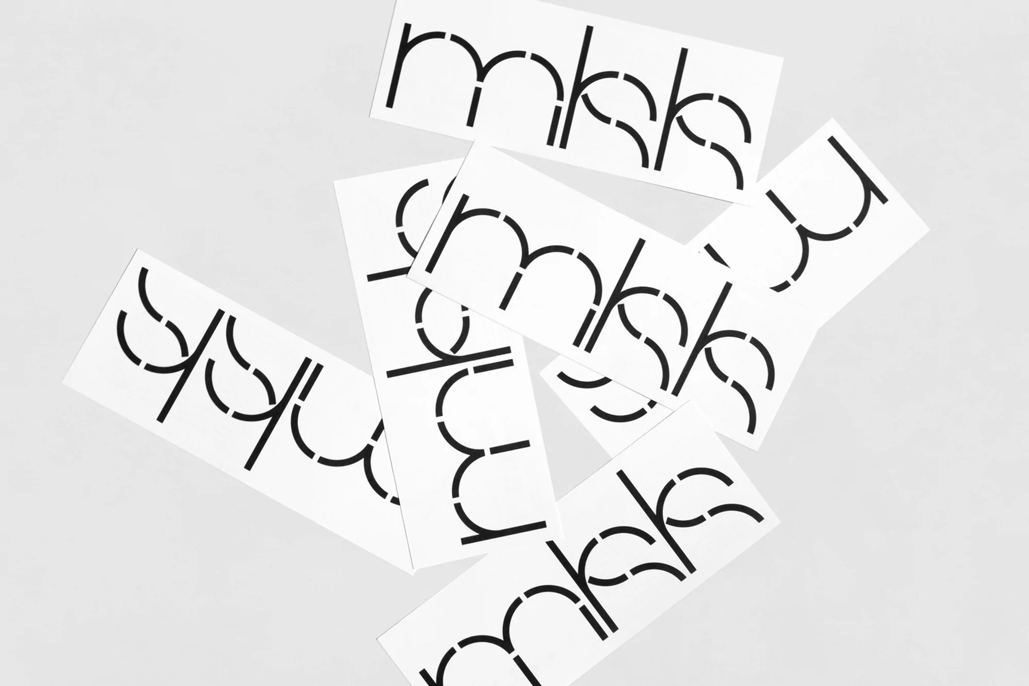 Several white rectangular cards displaying the text 'mkks' with a stencil-style font, creating a modern, minimalist abstract composition.