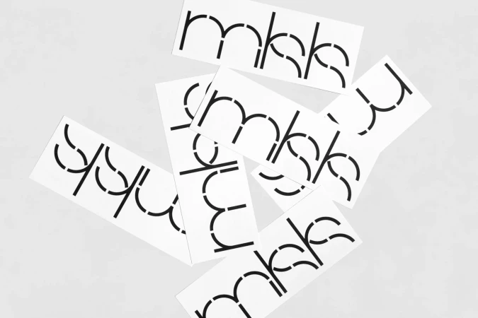 Several white rectangular cards displaying the text 'mkks' with a stencil-style font, creating a modern, minimalist abstract composition.