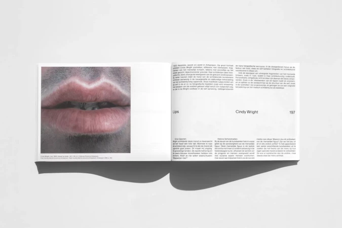 Open book spread featuring a close-up photograph of lips with white paint along the edge, accompanied by text on the opposite page.