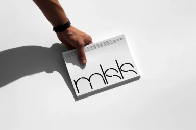 A hand holding a stack of white printed brochures with custom black typography against a clean white background.